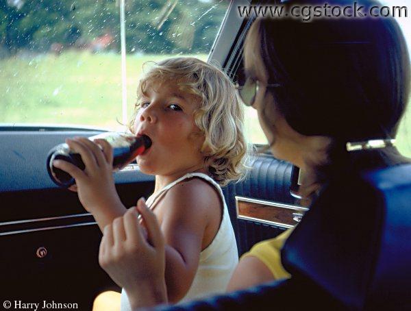 Boy on Mom's Lap in Car, Drinking Coke