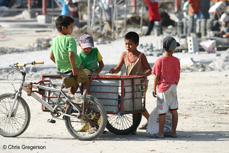 Photo of Four Boys Around a Tricycle Gathering Bric-a-brac from a Construction Site(5276)